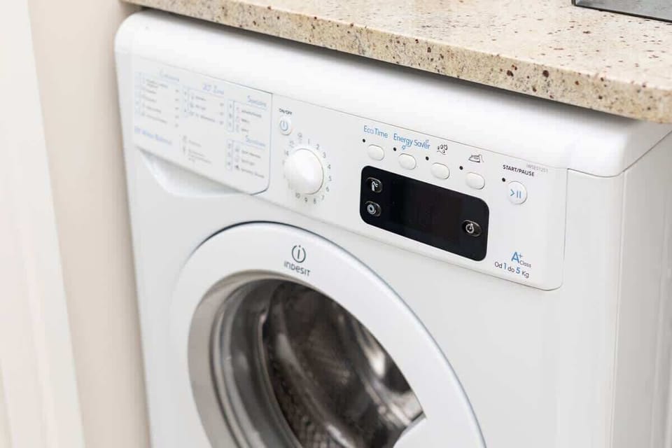 A built-in washing machine placed under the countertop, providing convenience for longer stays and easy laundry care.
