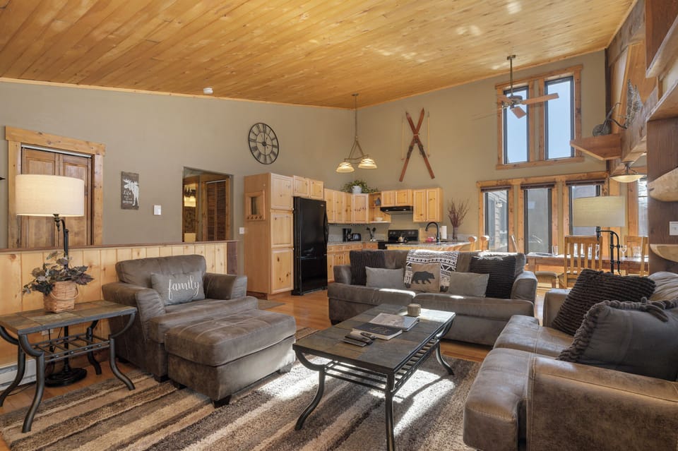 Relax in your cozy mountain retreat with rustic wood ceilings, plush sofas, and an open kitchen perfect for family gatherings.