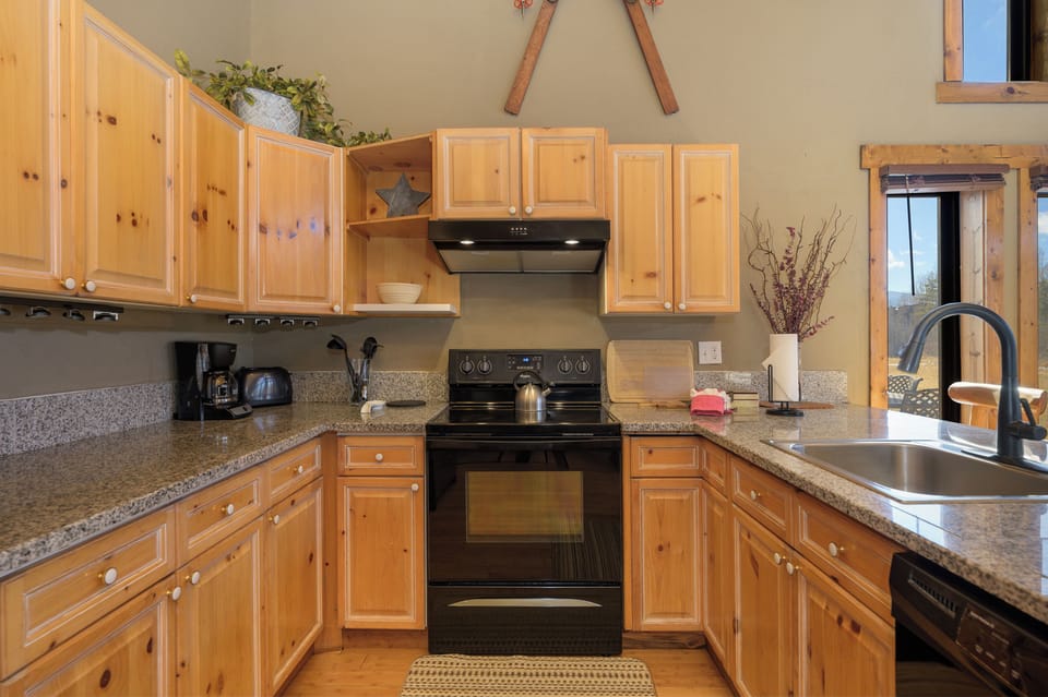 Cook with ease in your fully-equipped kitchen featuring warm wood cabinets, granite countertops, and modern appliances ready for memorable meals.