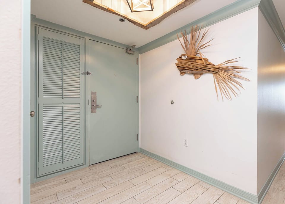 The entryway features a light teal door, decorative fish artwork, and light wood flooring, creating a welcoming atmosphere
