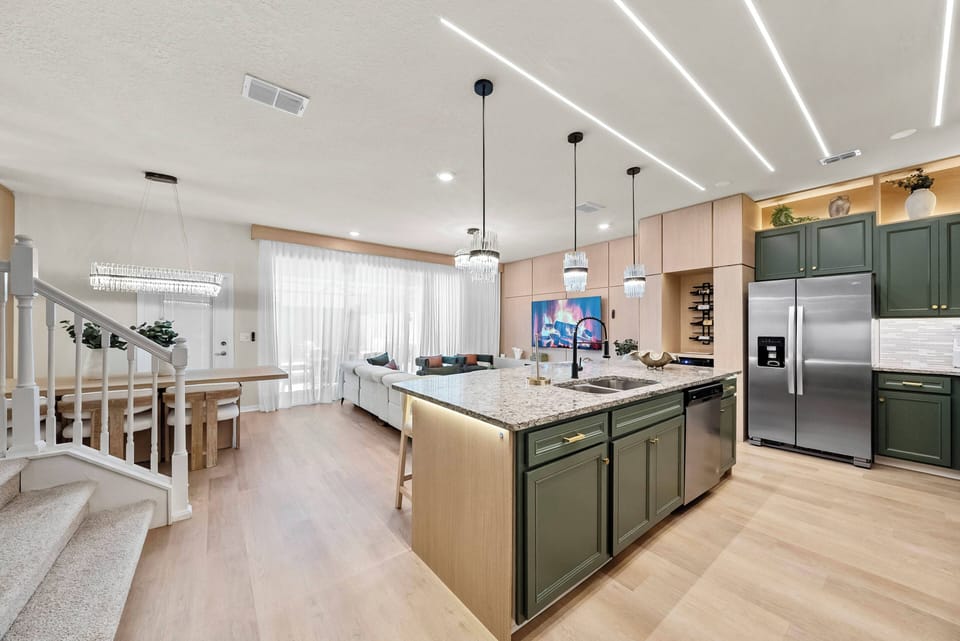 Discover a stylish kitchen with rich green cabinetry and sleek countertops that inspire culinary creativity. The open layout flows into a bright dining area, filled with natural light from large windows.