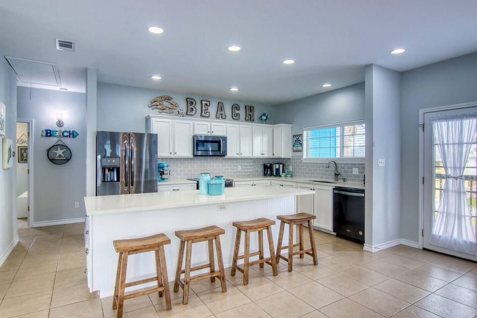 Kitchen island offers seating for four and ample workspace for preparing meals in the fully stocked kitchen.