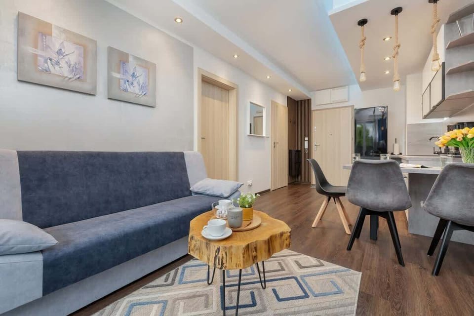 An open-concept living and dining area, showcasing a stylish sofa, coffee table, and a modern kitchen in the background.


