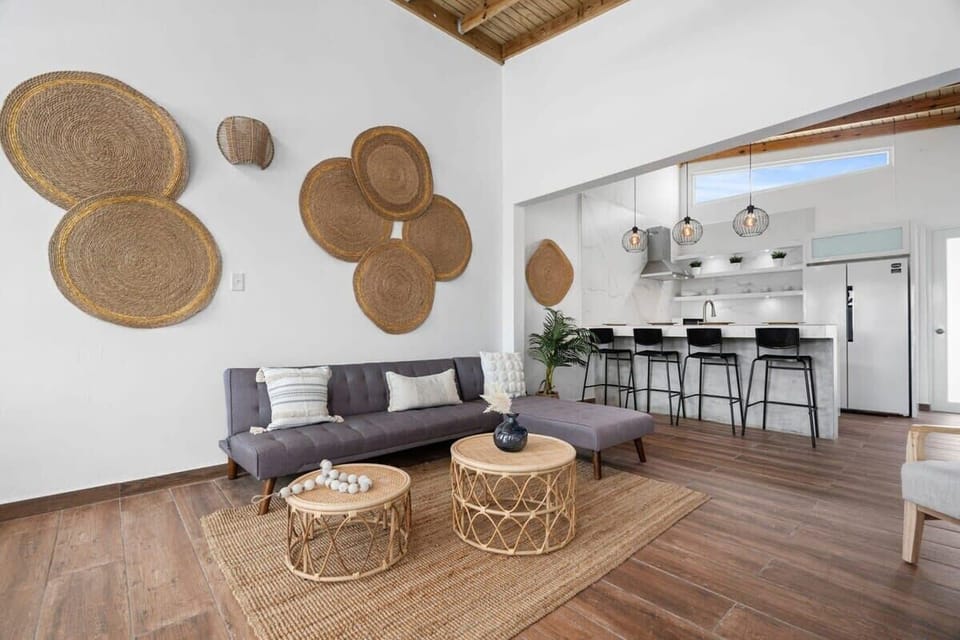 The living room has spectacular high ceiling with fan, a sectional sofa, flat screen smart TV and arm chair