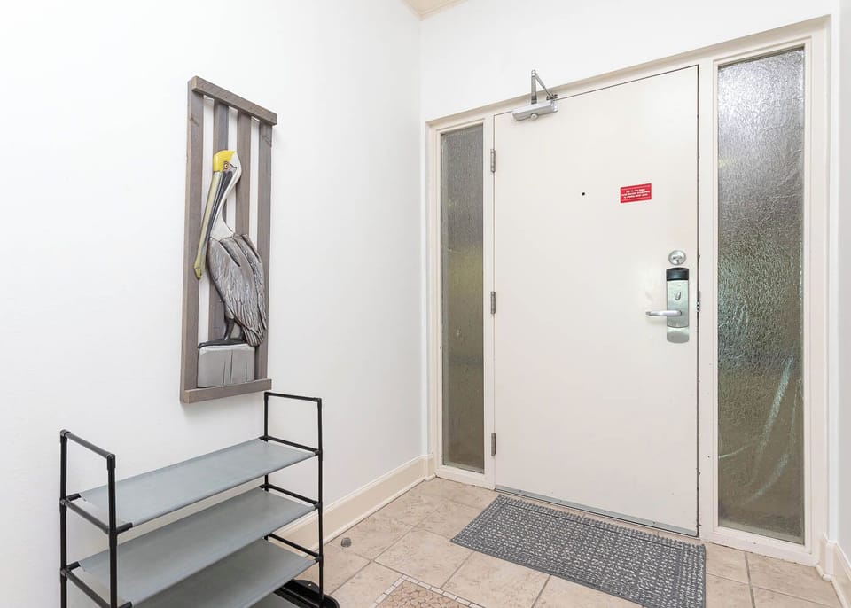 Step into a welcoming entryway adorned with a charming pelican artwork and practical storage for your beach gear