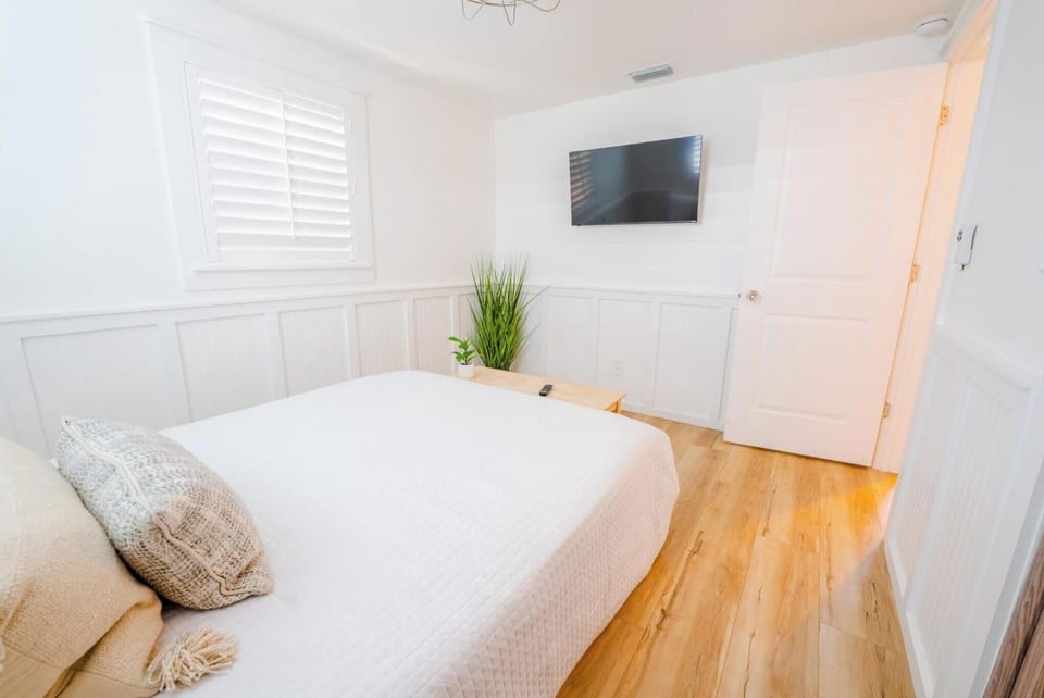 bright bedroom with a wall-mounted television and hardwood floors