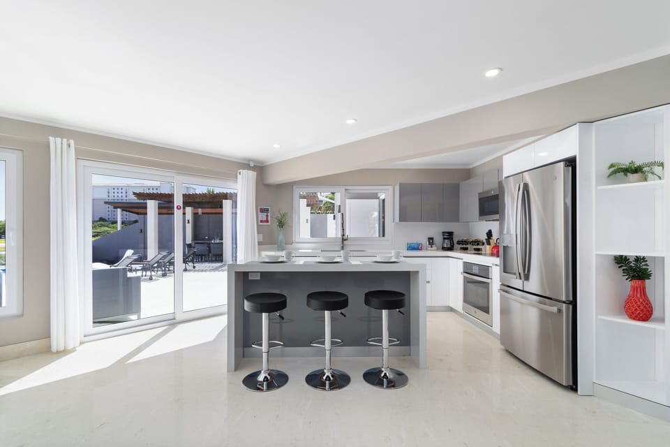 Clean Kitchen of the Villa in Noord Aruba - Kitchen has a breakfast bar - Modern kitchen with sleek, stainless steel appliances - Bar style High Chairs - Smart use of space with versatile storage solutions - Touch of nature with potted plants