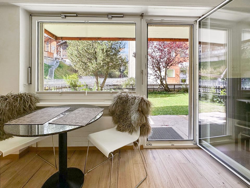 Small table with chairs and view of the sunny terrace.