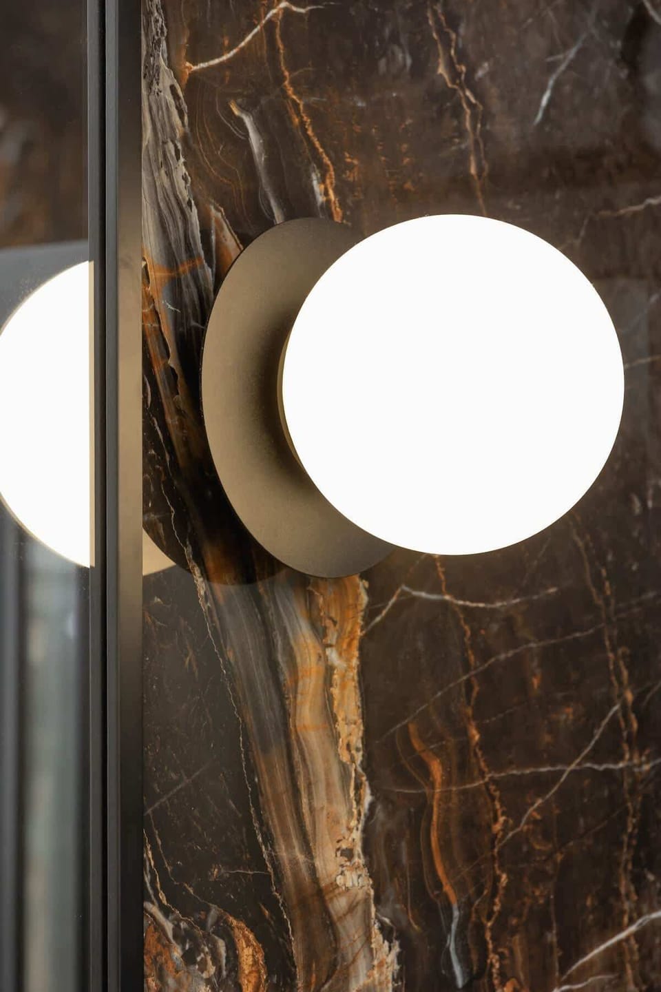 The spacious bathroom fitted with a washing machine, boasting eye-catching marble walls and modern black accents.
