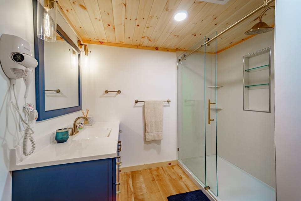 The lower-level full bathroom features a spacious 36" x 60" walk-in shower and beautiful blue wood cabinetry.