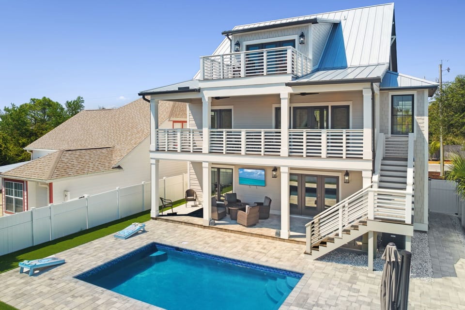 Private saltwater pool with lounge seating—perfect for relaxing after beach days, plus a fenced-in backyard & cornhole.