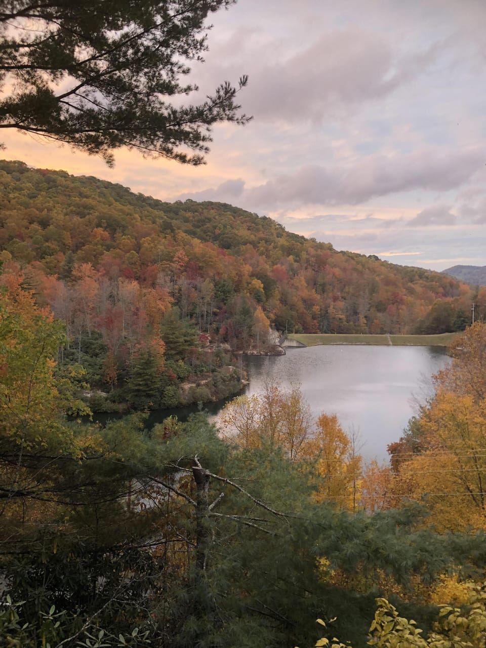 Peak fall color wrapping every hillside, a still mountain lake below. This is the view waiting at Lake Overlook.