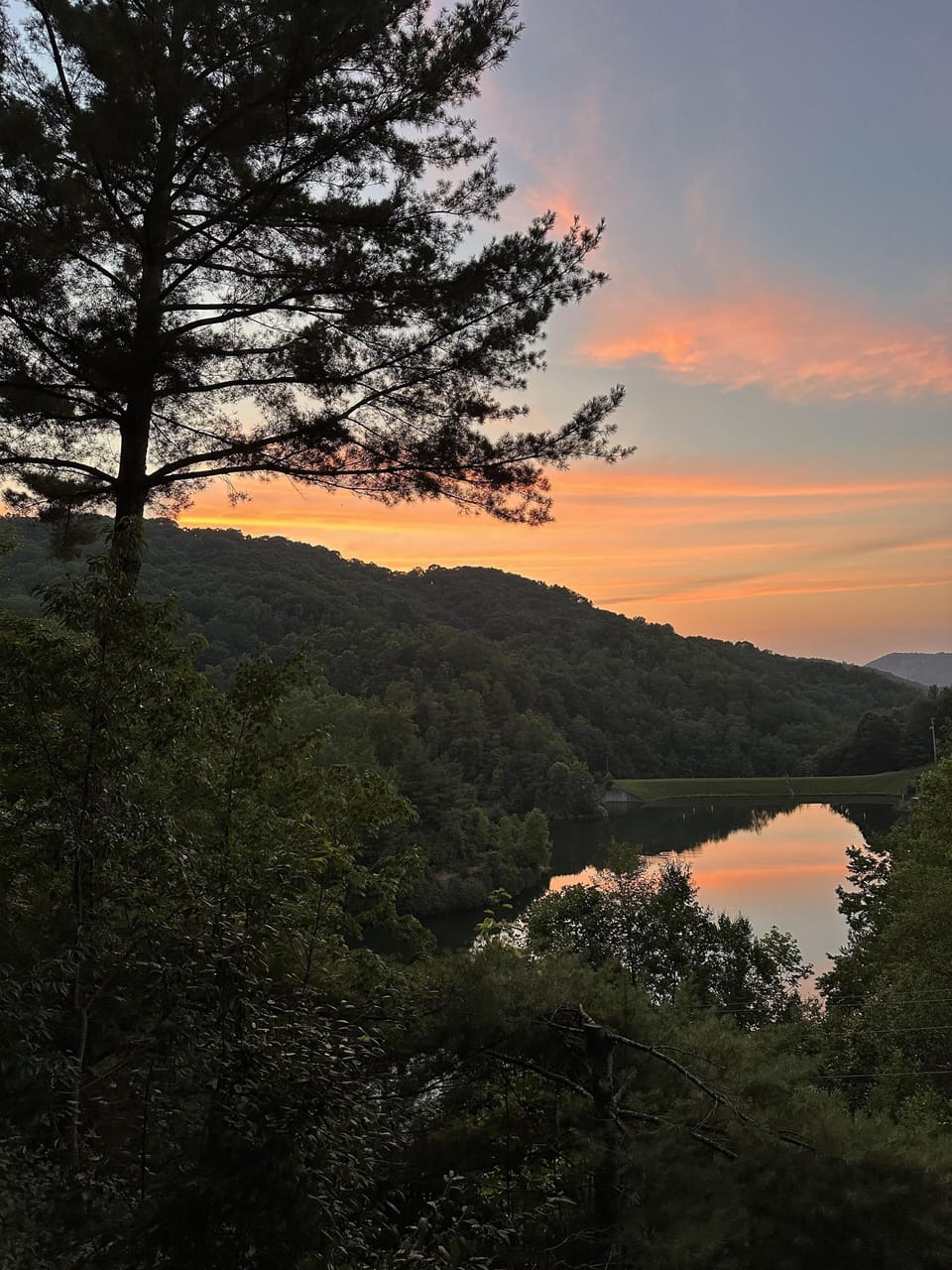 Golden hour over the lake, framed by pines and rolling Blue Ridge hills. Evenings at Lake Overlook are something else.