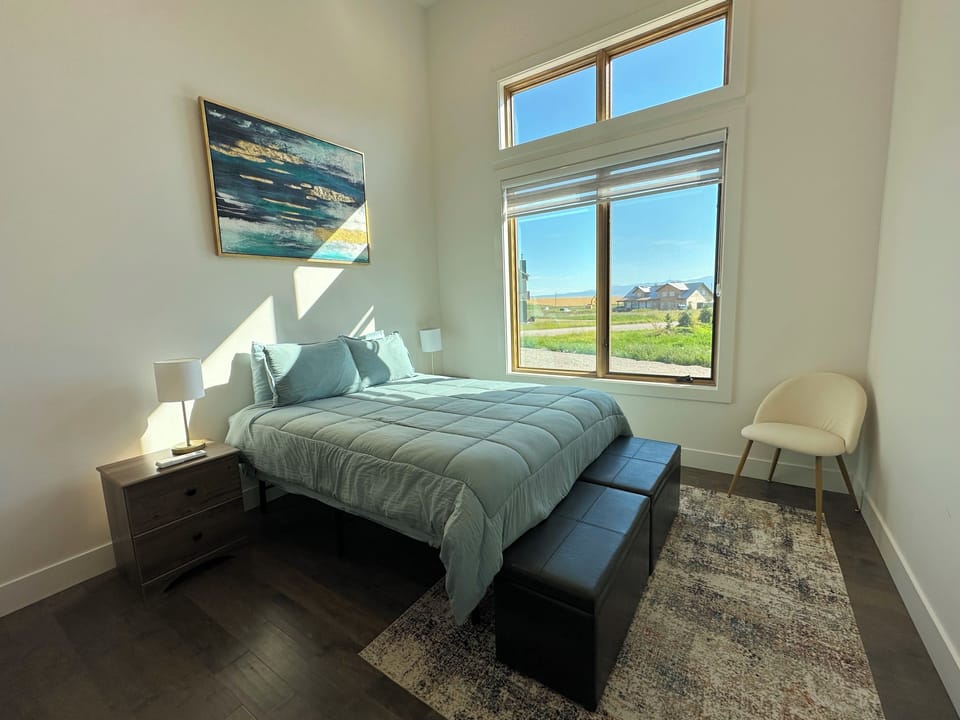 The bedroom features a queen bed, a spacious closet, and a peek of the Tetons.
