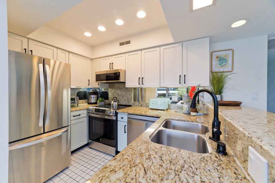 Fully remodeled kitchen with upgraded appliances, spacious breakfast bar, and everything needed to prepare meals during your Kona getaway.