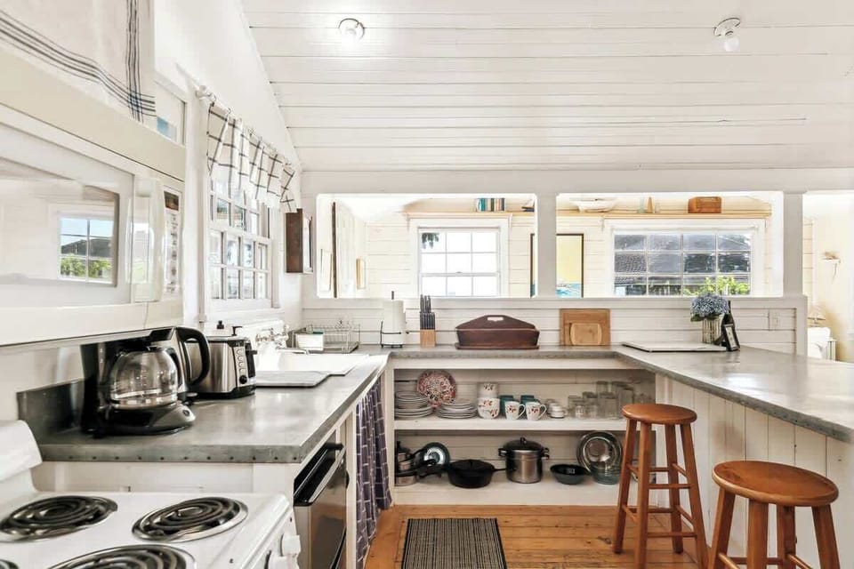 Functional kitchen with breakfast bar seating and open shelves, creating a welcoming space for cooking and casual dining.