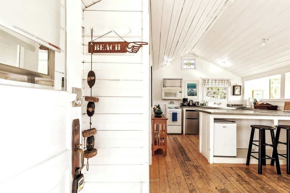 Step into a bright beach-inspired space with warm wood floors, open kitchen, and relaxed coastal charm that instantly makes you feel at home.