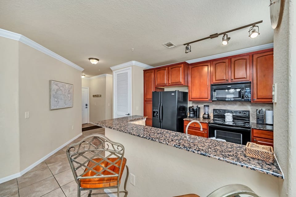 Entryway and open kitchen view featuring granite counters, wood cabinetry, and a breakfast bar.
