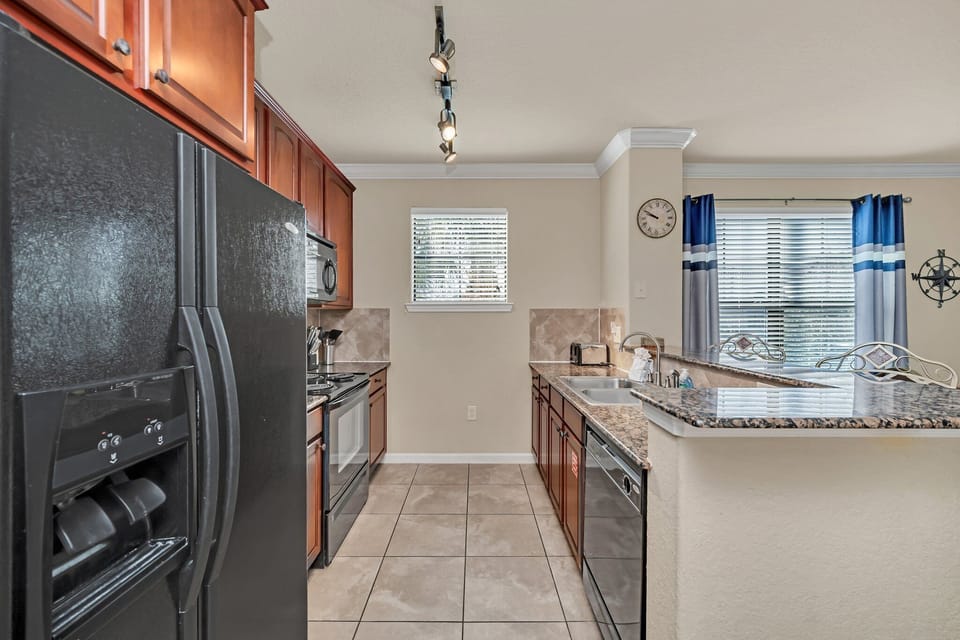 Sleek kitchen with black appliances, tile floors, and large windows for natural light.