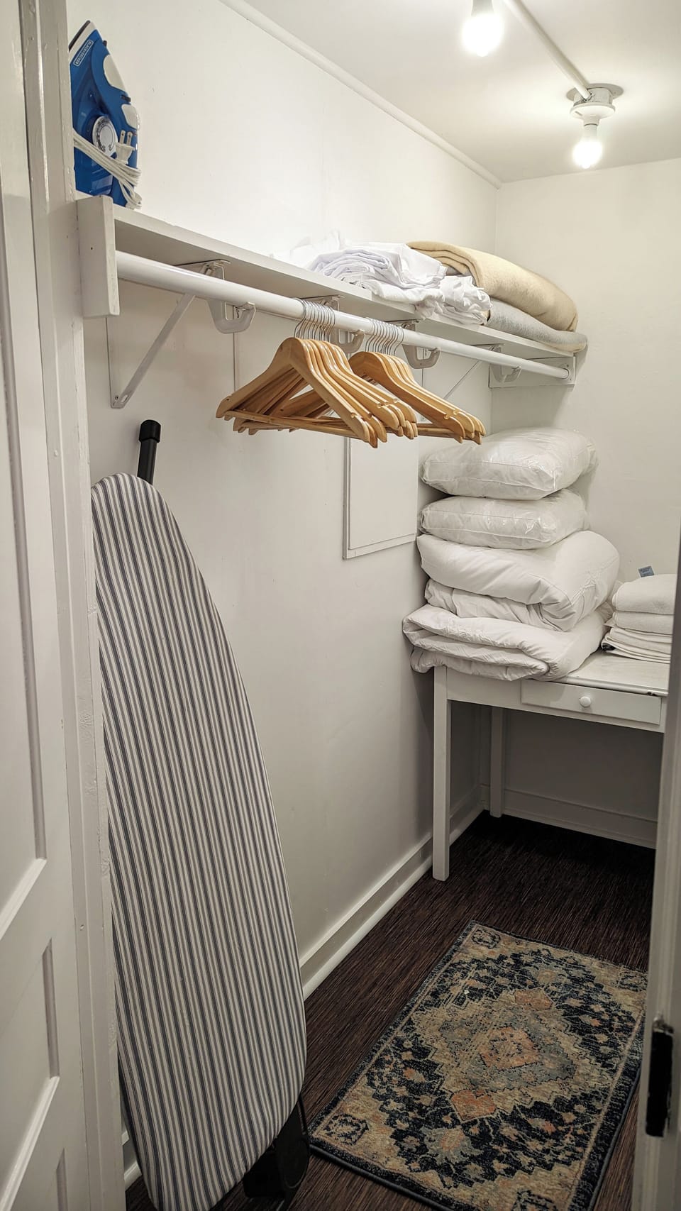 Walk-in closet with extra towels and sheets ironing board and iron.