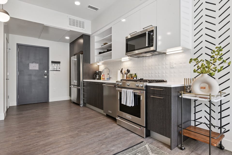 Fully equipped kitchen with stainless steel appliances, dishwasher, and full cookware at EcoLoft Retreat.