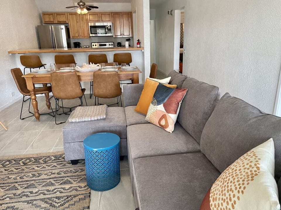 An open plan layout with a full kitchen, generous sectional sofa, and dining space