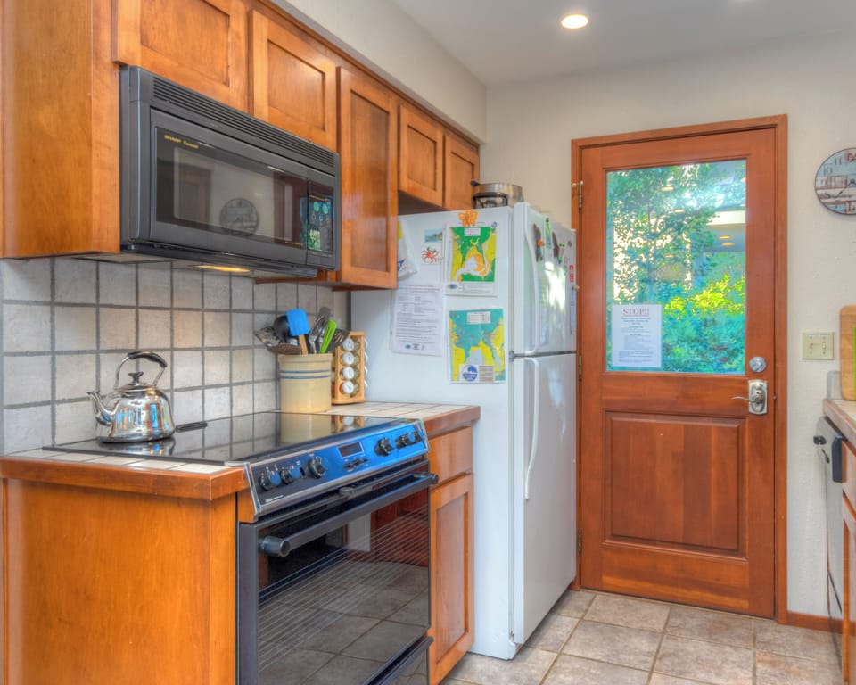 Fully equipped kitchen with access out to back deck with hot tub and outdoor dining area.