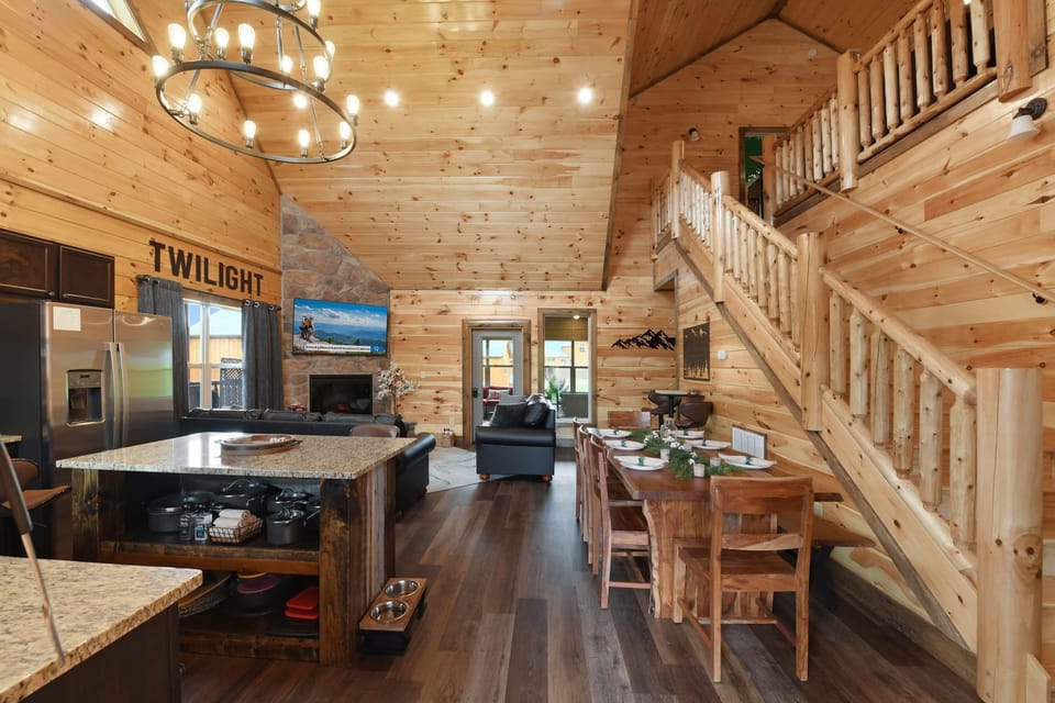 Rustic cabin interior featuring a spacious dining area and cozy living room with stone fireplace.