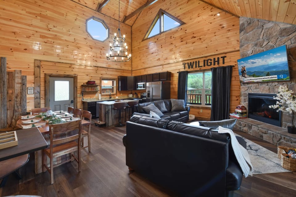 Rustic living area with vaulted ceilings, stone fireplace, and open kitchen for family gatherings.