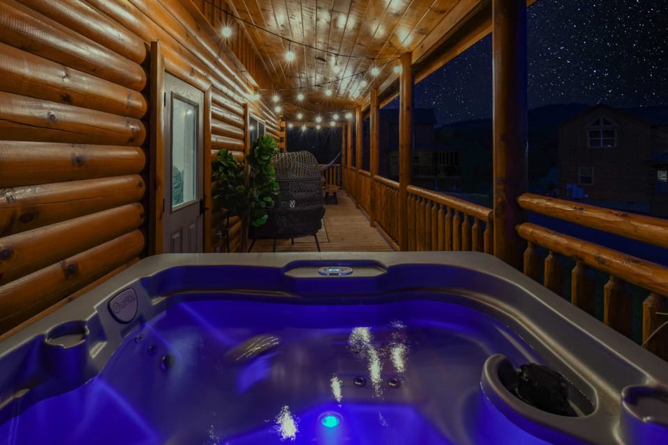 Relax in the illuminated hot tub on the rustic wooden porch under a starry night sky.
