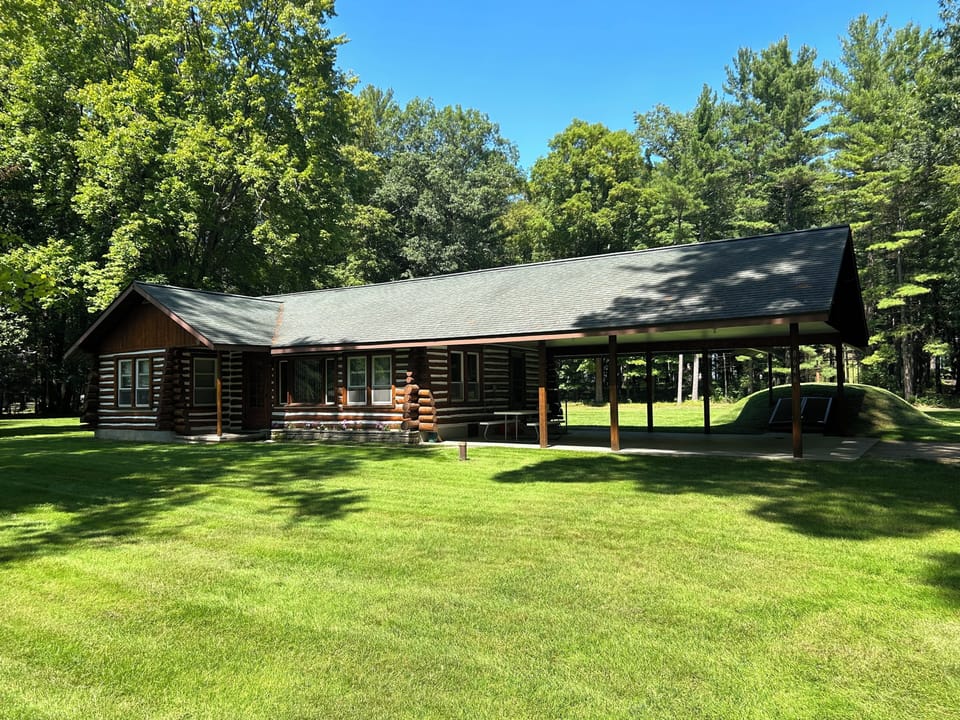 EXTERIOR:  Another view of the front of the cabin in summer.