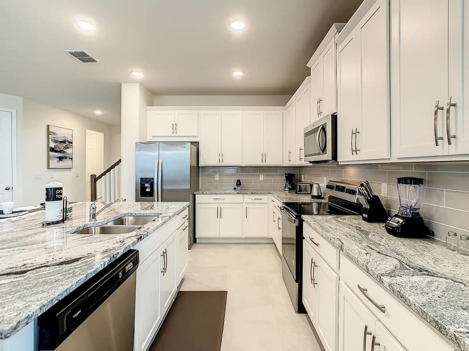 A fully stocked kitchen featuring two sets of pots and pans, a Keurig machine, and stainless steel appliances.