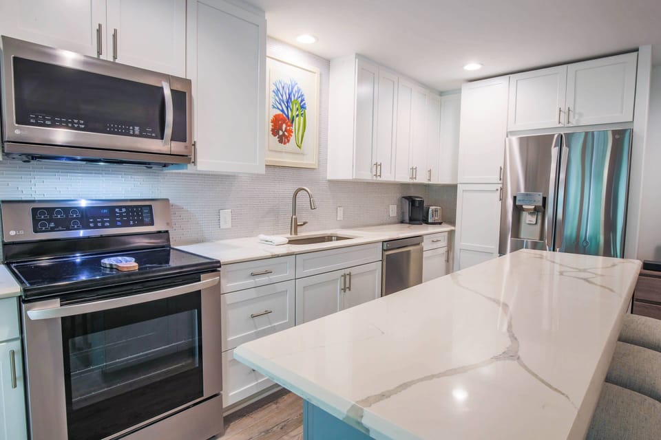 This gorgeous kitchen features stainless steel appliances, quartz counters and a central island with 4 stools.