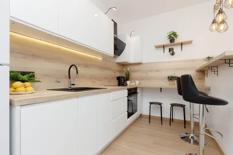 A fully equipped kitchen with white cabinets, a fridge, and a sleek design complemented by wooden accents.

