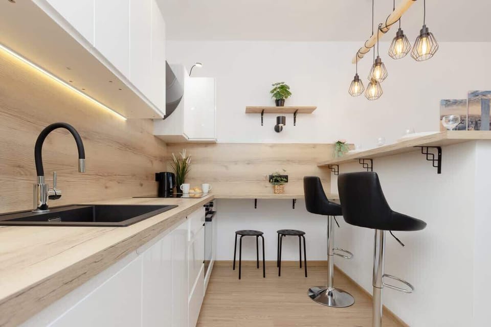 A modern kitchenette with black fixtures, wooden countertops, and under-cabinet lighting for a sleek look.
