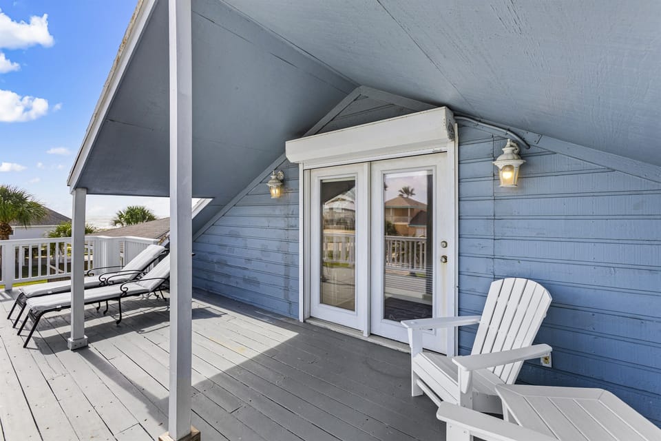 The upper level large bedroom has a private balcony with lounge chairs and Adirondack chairs