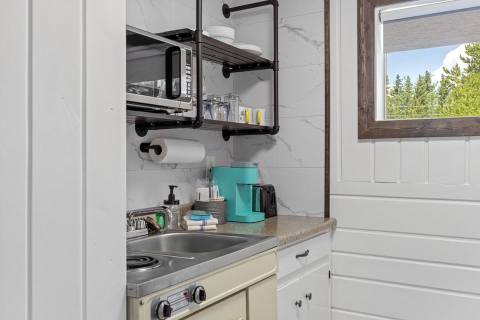 Kitchenette with two top electric stove, microwave, Keurig and dinnerware