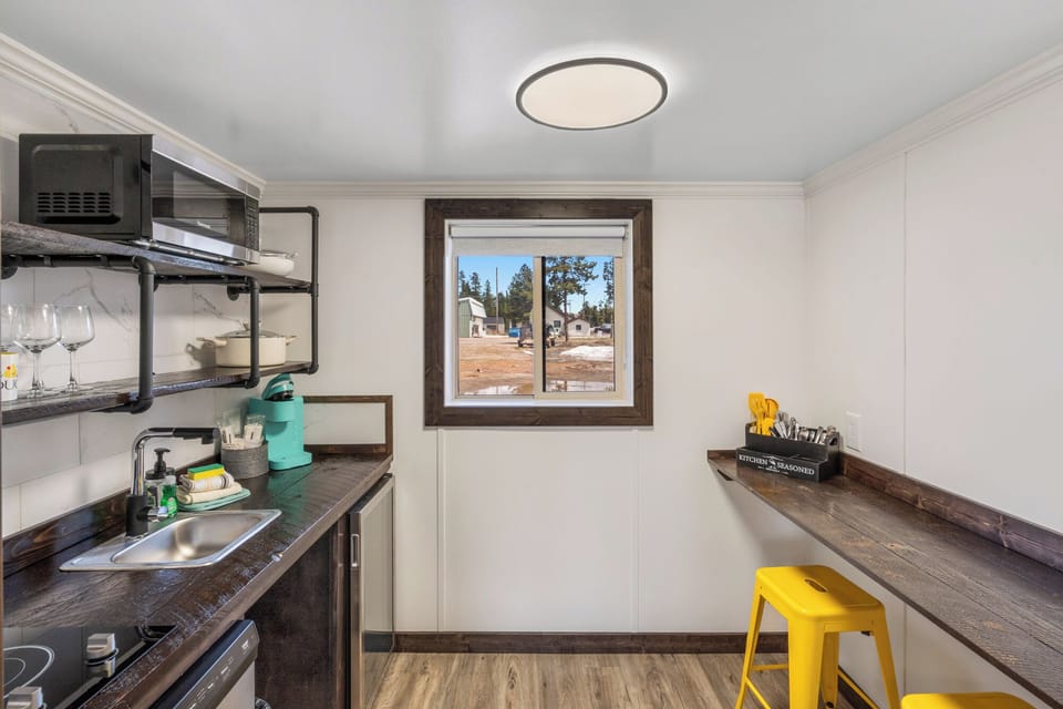 Kitchenette with dishwasher, mini fridge, microwave, two burner electric stovetop, dinner wear, utensils and bar style countertop for eating meals
