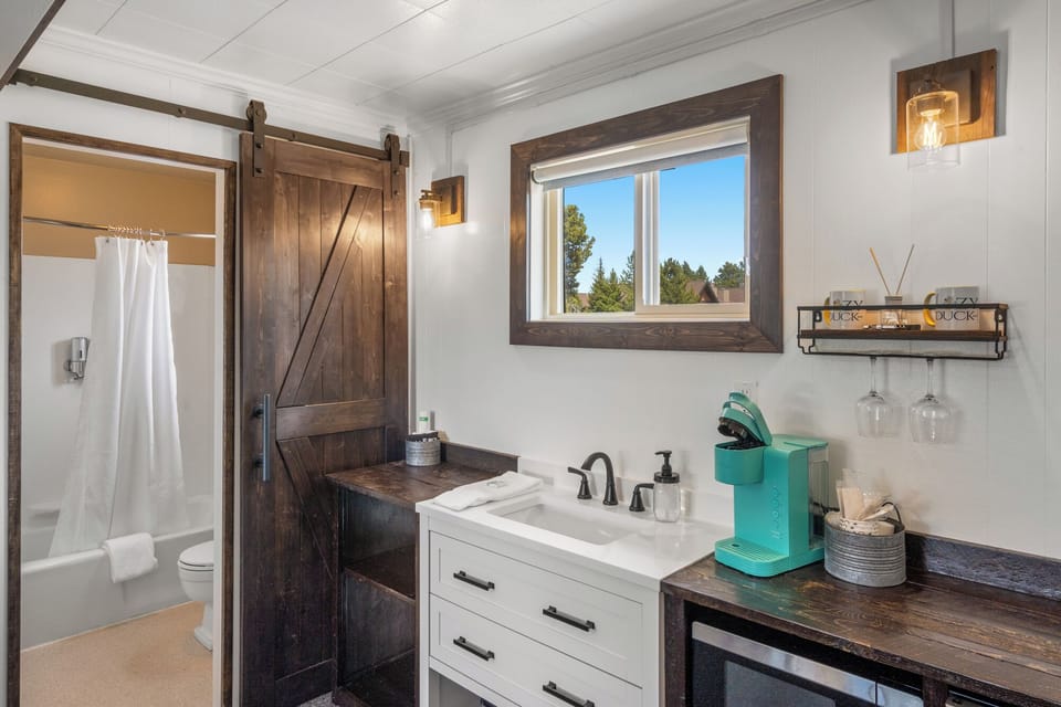 Bathroom separated by barn style door, which includes sink, Keurig coffee machine and microwave in main room