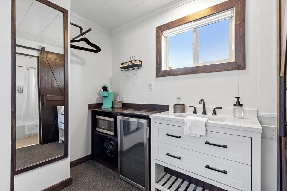 Bathroom sink, mini fridge, microwave, kurig coffee maker and full-length mirror