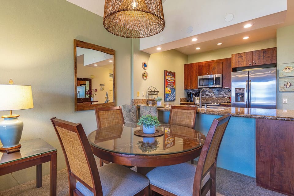 Gather around the elegant dining table where meals become memories, with the fully-equipped kitchen just steps away for effortless entertaining. Warm wood tones and tropical accents create an inviting space where your group can connect.