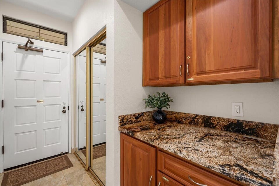 Your entry features rich wood cabinetry and granite countertops, providing convenient storage and prep space right as you arrive.