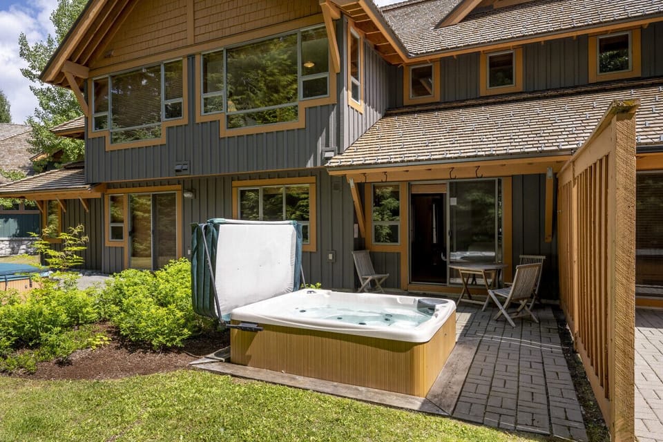 A view of the private hot tub in the summer.  Plenty of backyard space with green grass for everyone to enjoy - especially kids!