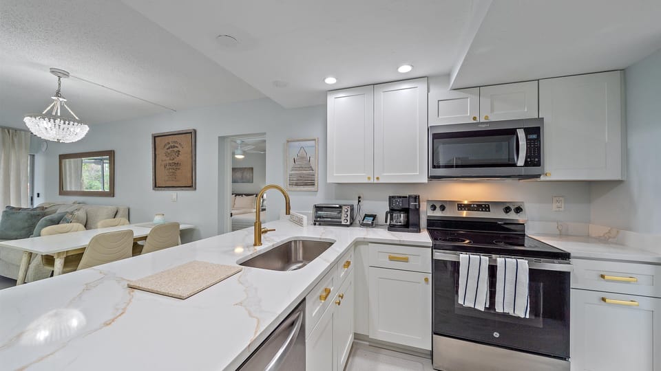 A sleek kitchen with white cabinets, a modern faucet, and a large countertop. It has an open layout to the dining area.