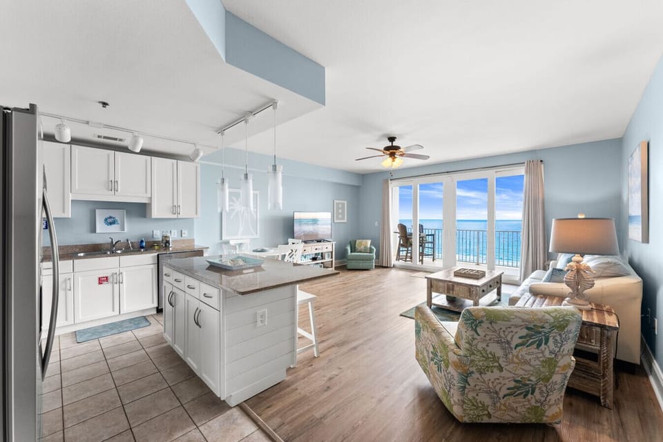 Spacious open-concept living area with stunning Gulf views through floor-to-ceiling balcony doors.