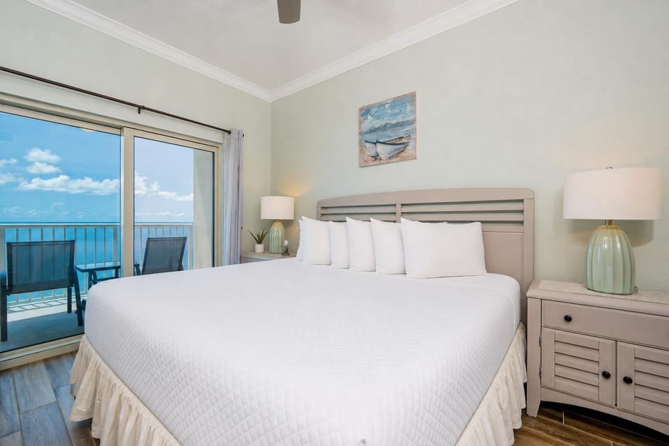 Master bedroom featuring a plush king bed and a stunning balcony view of the tranquil blue waters
