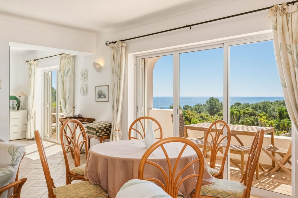 A dining table with four chairs in the holiday flat on the upper floor of the uniquely situated Casa Galo Verde, offering a stunning, unobstructed view of the sea across the garden.