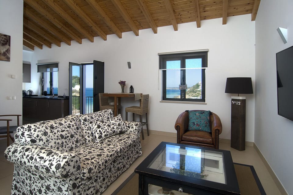 The living room of Casa Sereia Mar offers a fantastic view of the sea and the beach of Salema as well as the town itself. It is furnished with a sofa and a TV as well as a coffee table. There is a small dining table for two against the wall.