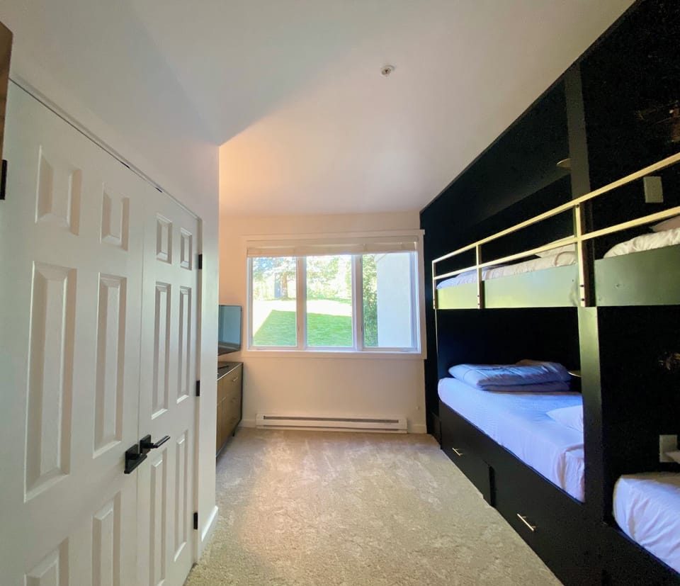 The bunk room has a large closet, dresser and smart TV