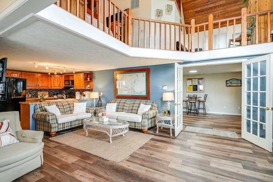 Living room with a glimpse of the gaming area and 2nd story balcony.